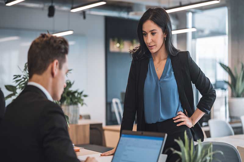 A person hesitating to approach a colleague in a modern office.